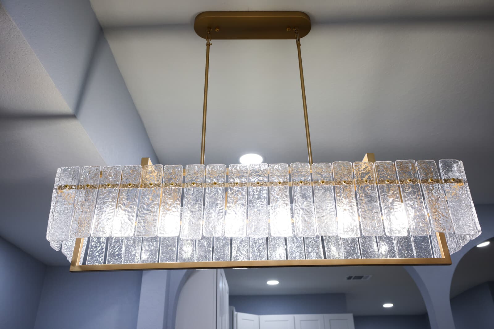 Detail of the textured glass and brass linear pendant above the dining table