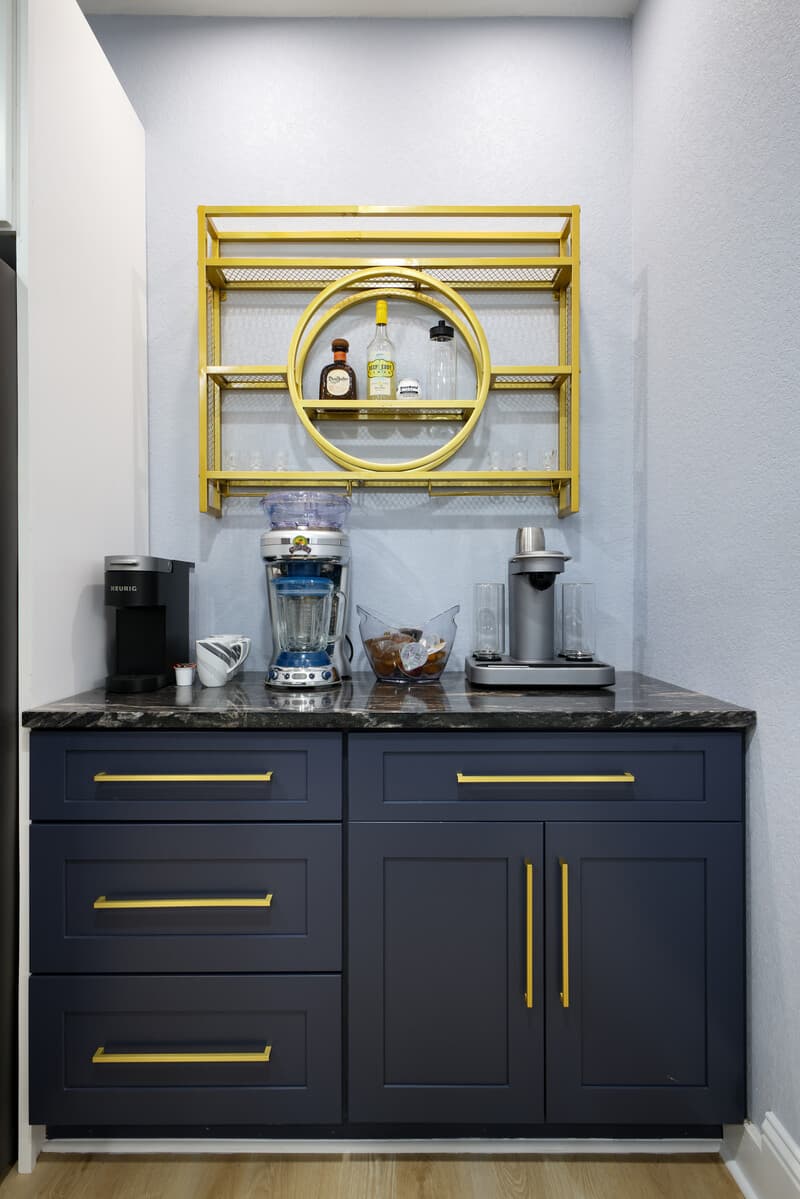 Built-in coffee bar in navy cabinetry with brass pulls and open shelving