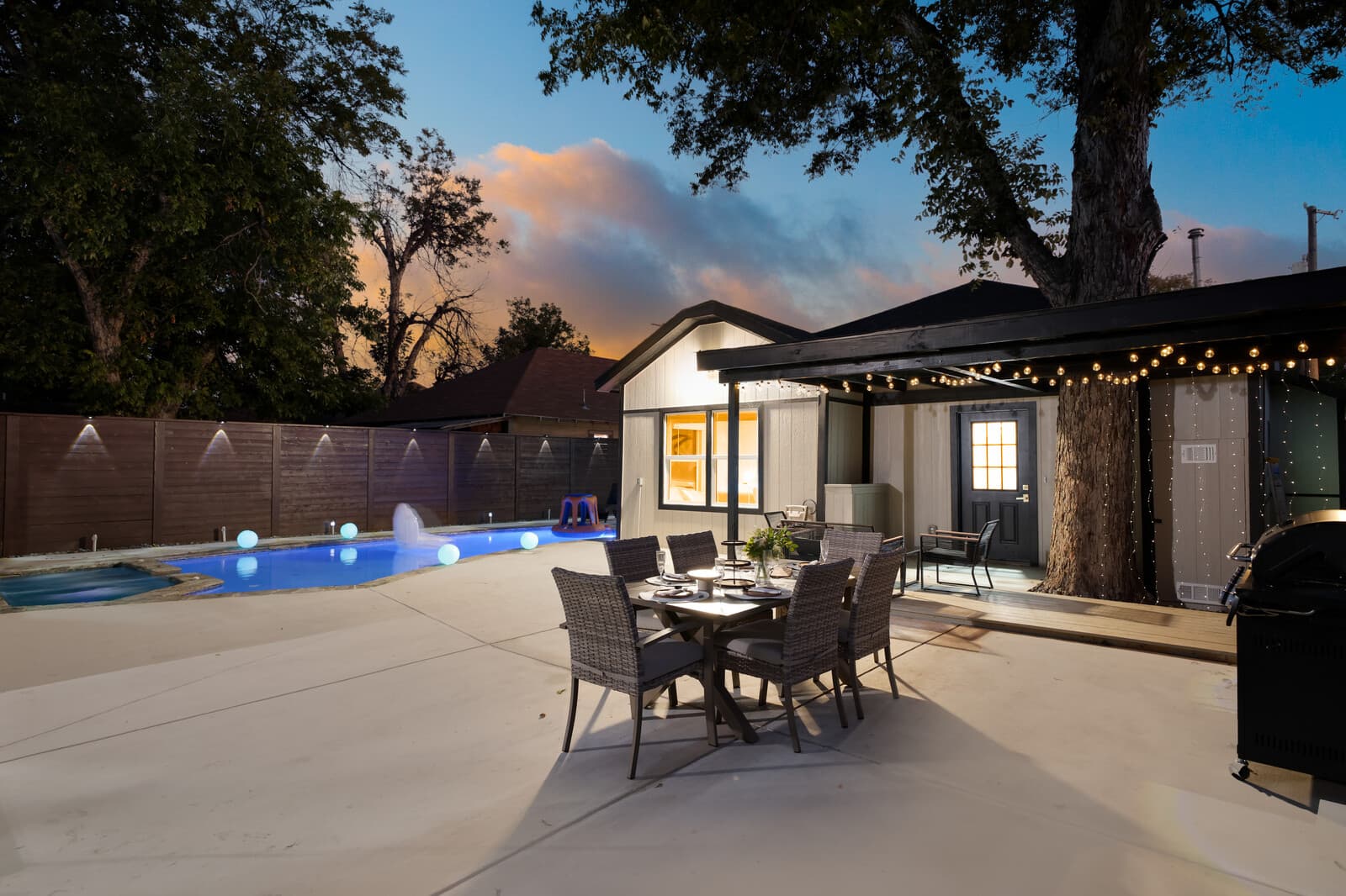 Wide view of the pool, patio and mature oak between the two buildings