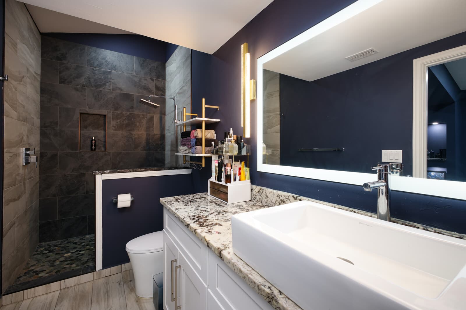 ADU bathroom with a dark tiled shower and a backlit mirror
