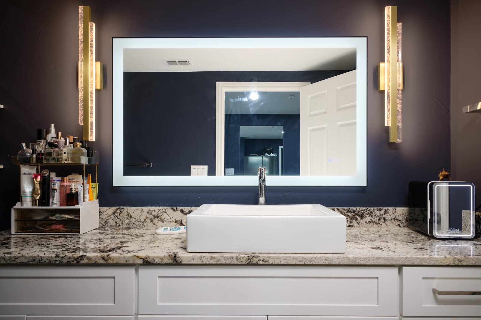 ADU vanity with a vessel basin, stone counter and backlit mirror